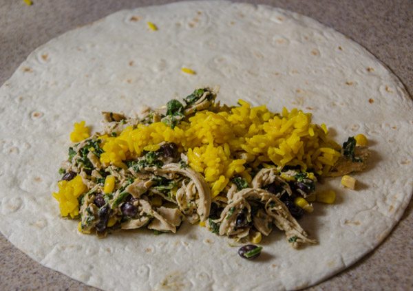 LR_White Chicken Enchiladas_prep-15 Prepare enchiladas. Lay out all 8 tortillas. Divide chicken/spinach mixture evenly between them. Add 2 heaping spoonfuls of yellow rice to each (more or less to taste). Add a sprinkle of cheese to each.