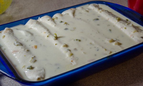 LR_White Chicken Enchiladas_prep17-1 Pour white sauce over enchiladas (baking dish will be very full). Sprinkle with extra cheese if desired.