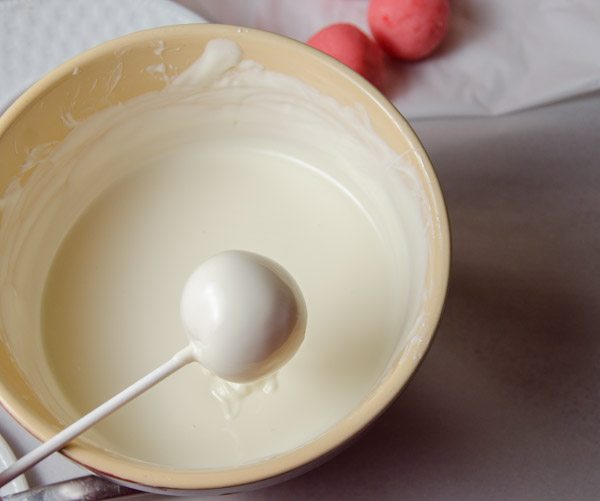 LR_Mummies_prep8 Dip each chilled cake bite straight down into the melted coating until the cake ball is completely covered and sealed. Turn at an angle and tap slightly to remove excess chocolate.