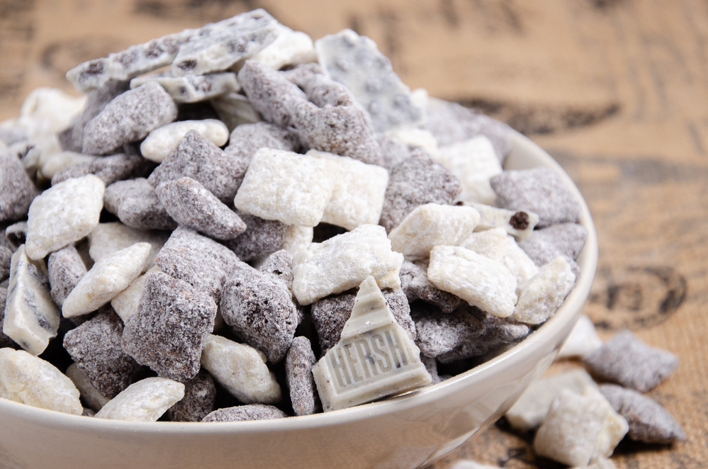 Cookies and cream muddy buddies in a white bowl and burlap background.