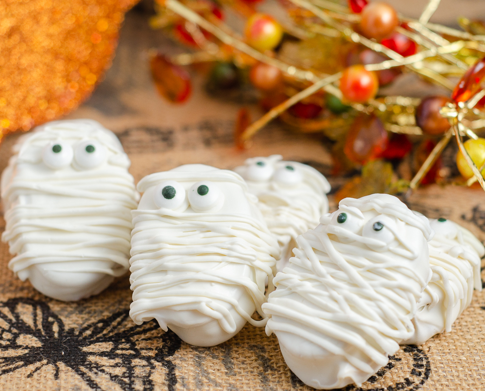 Halloween Mummies. White chocolate, peanut butter filling, decorated for Halloween. No-bake dessert that is cute and so delicious! #halloween #halloweenmummies #mummies #peanutbutter #whitechocolate