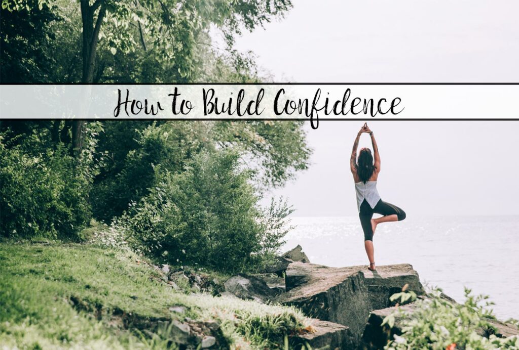 Featured image for article on how to build confidence. Woman in yoga post next to water.