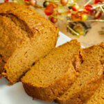 Loaf of pumpkin bread with three slices spread out.