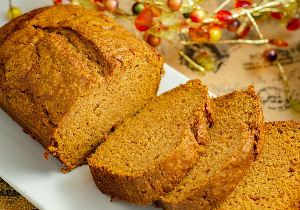 Loaf of pumpkin bread with three slices spread out.