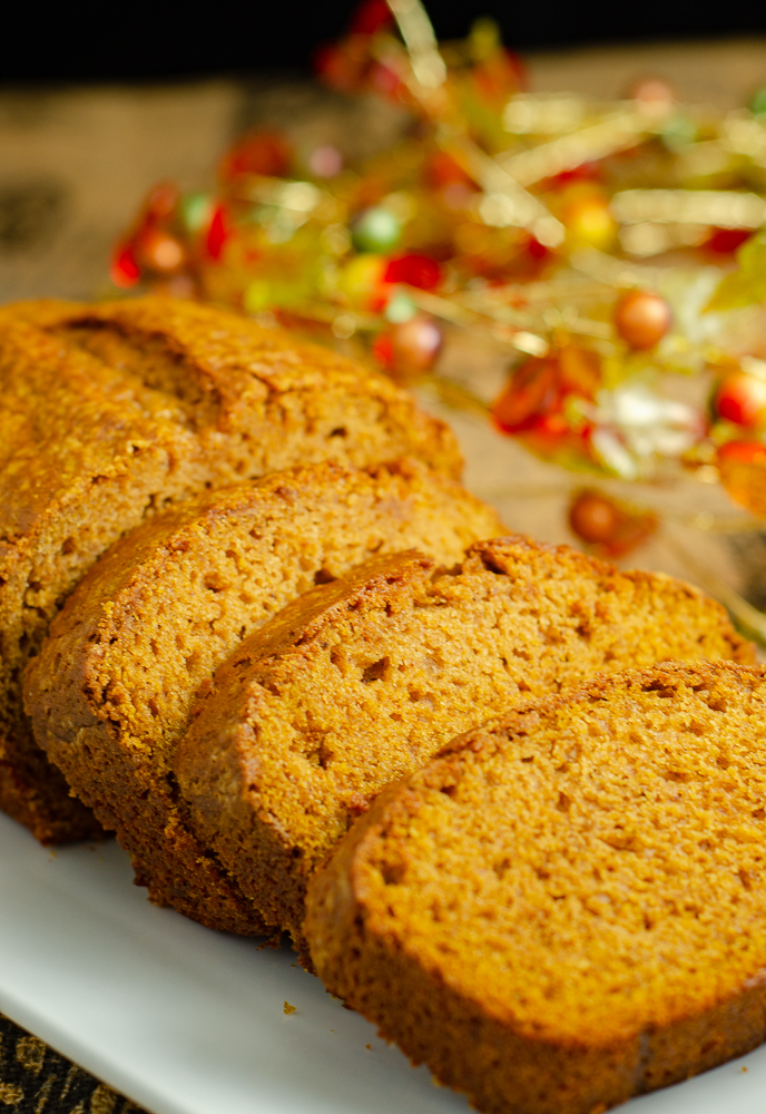 Vertical image: Loaf of pumpkin bread with three slices spread out.