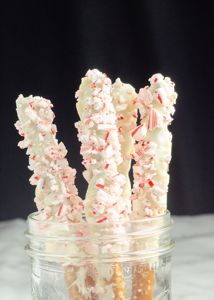 White chocolate peppermint pretzels vertical in a mason jar. Marble bottom and black background.