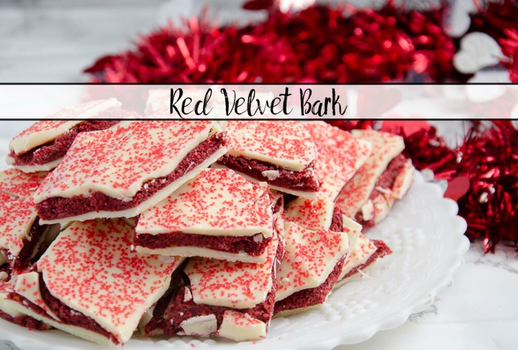 Featured image for red velvet bark. Close-up of bark piled on white plate with red tinsel in background.
