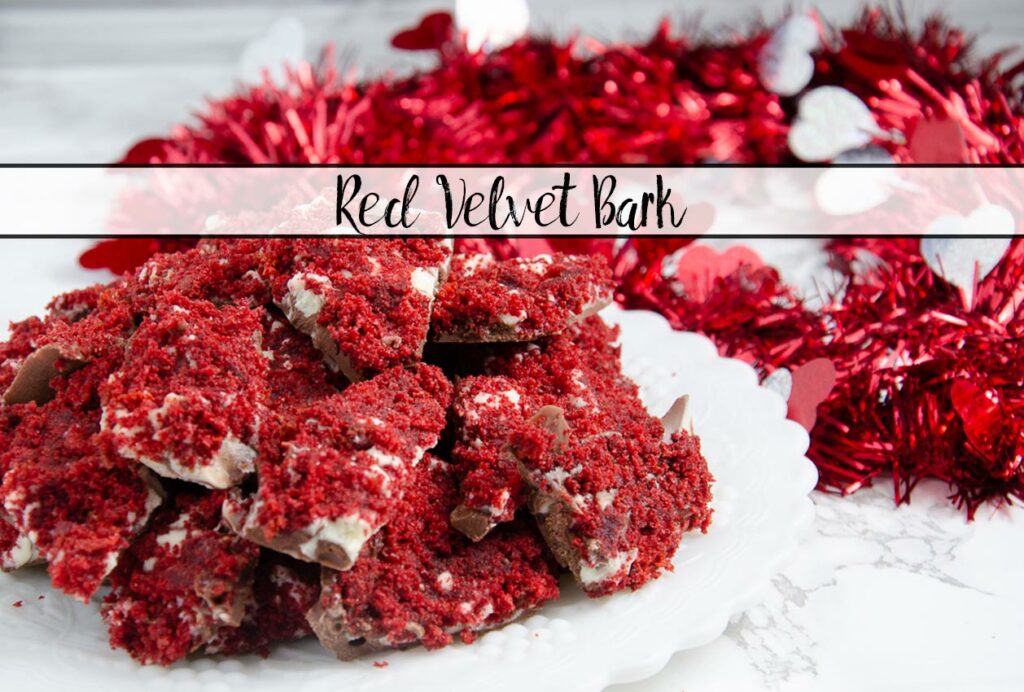 Featured image for red velvet bark. Close-up of bark piled on white plate with red tinsel in background.