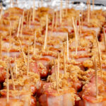 Bacon wrapped little smokies covered in brown sugar lined up in baking pan. Cooked.