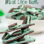 Pin image for mint oreo bark. Stack of mint oreo bark in foreground. White bowl full of mint oreo bark with green tinsel in background.