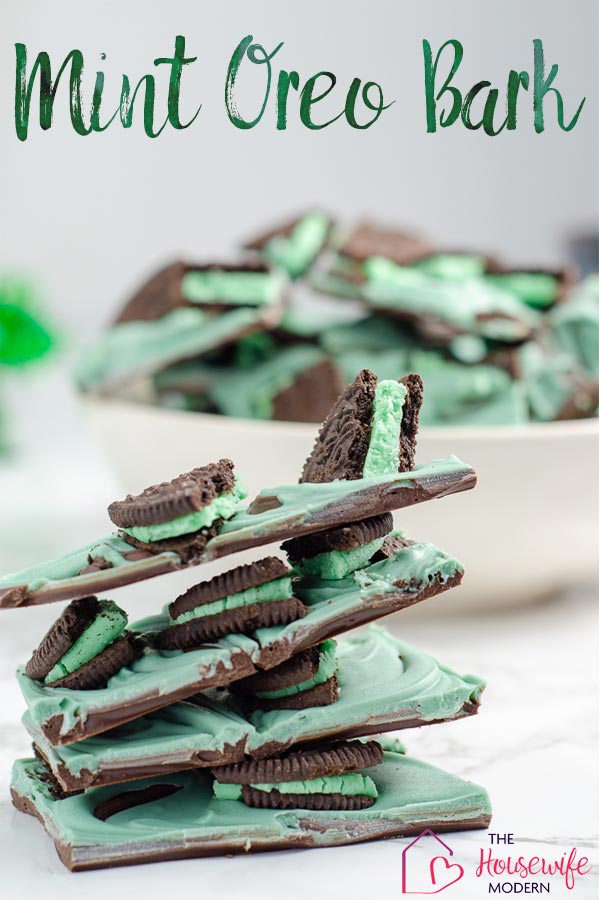 Pin image for mint oreo bark. Stack of mint oreo bark in foreground. White bowl full of mint oreo bark with green tinsel in background.