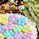 Spring flower pretzel bites on white plate with egg & flower foliage.