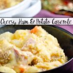 Featured image for cheesy ham and potato casserole. Blue bowl full of casserole with purple napkin in background.