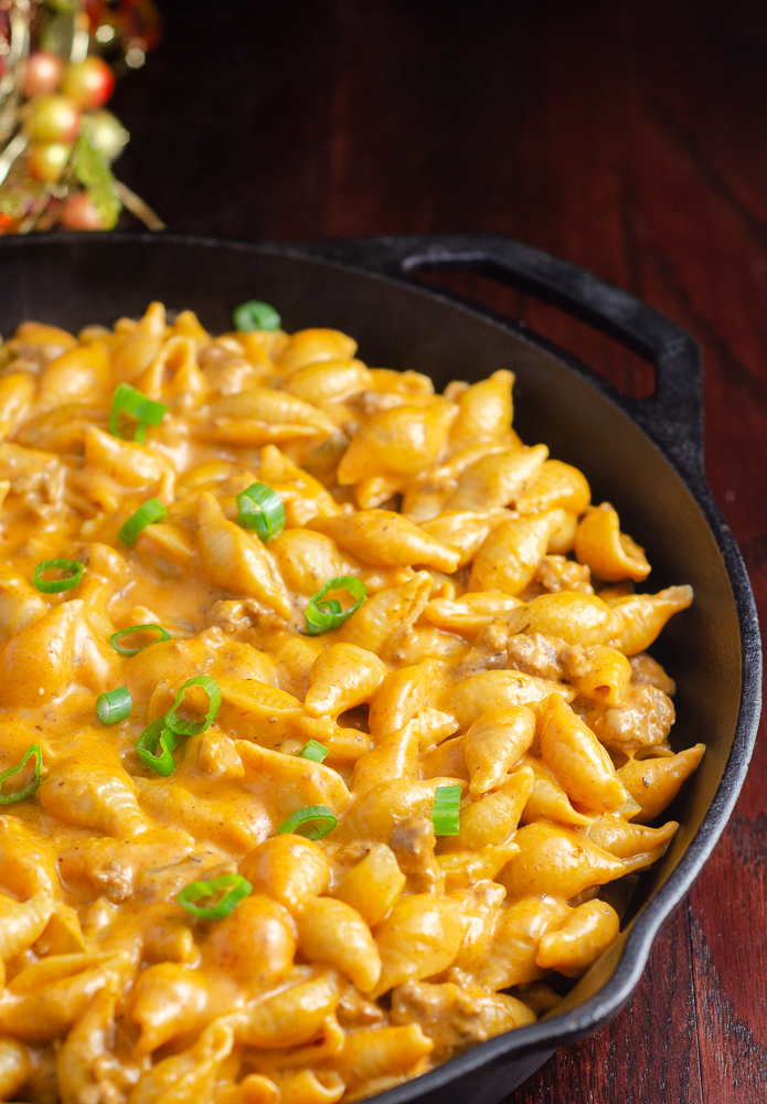 Homemade hamburger helper in cast-iron skillet on wood planks. Cheeseburger macaroni version.