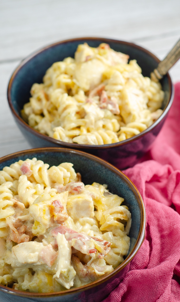 Two dark blue stoneware bowls of casserole with red cheesecloth on side. Vertical image