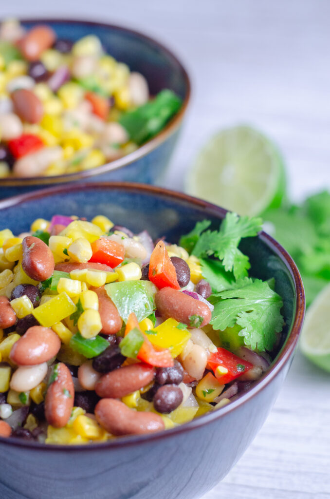 Easy Mexican bean salad is packed with corn, three kinds of beans, colorful peppers, and cilantro tossed in a fresh lime dressing. This make ahead healthy side dish is perfect for summer BBQs, potlucks, picnics, and meal prep.
